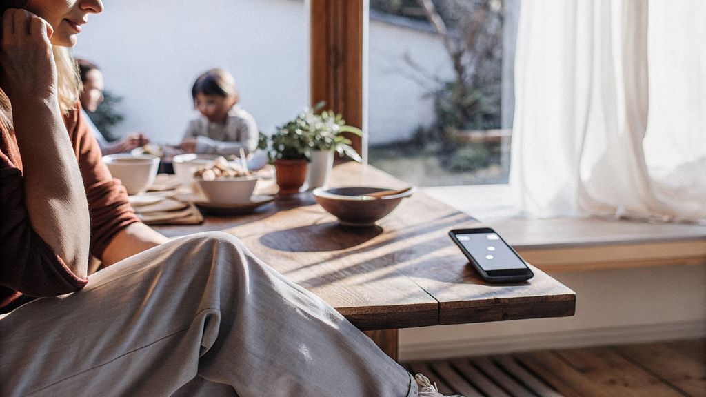 person staring out a window while phone notifications glow
