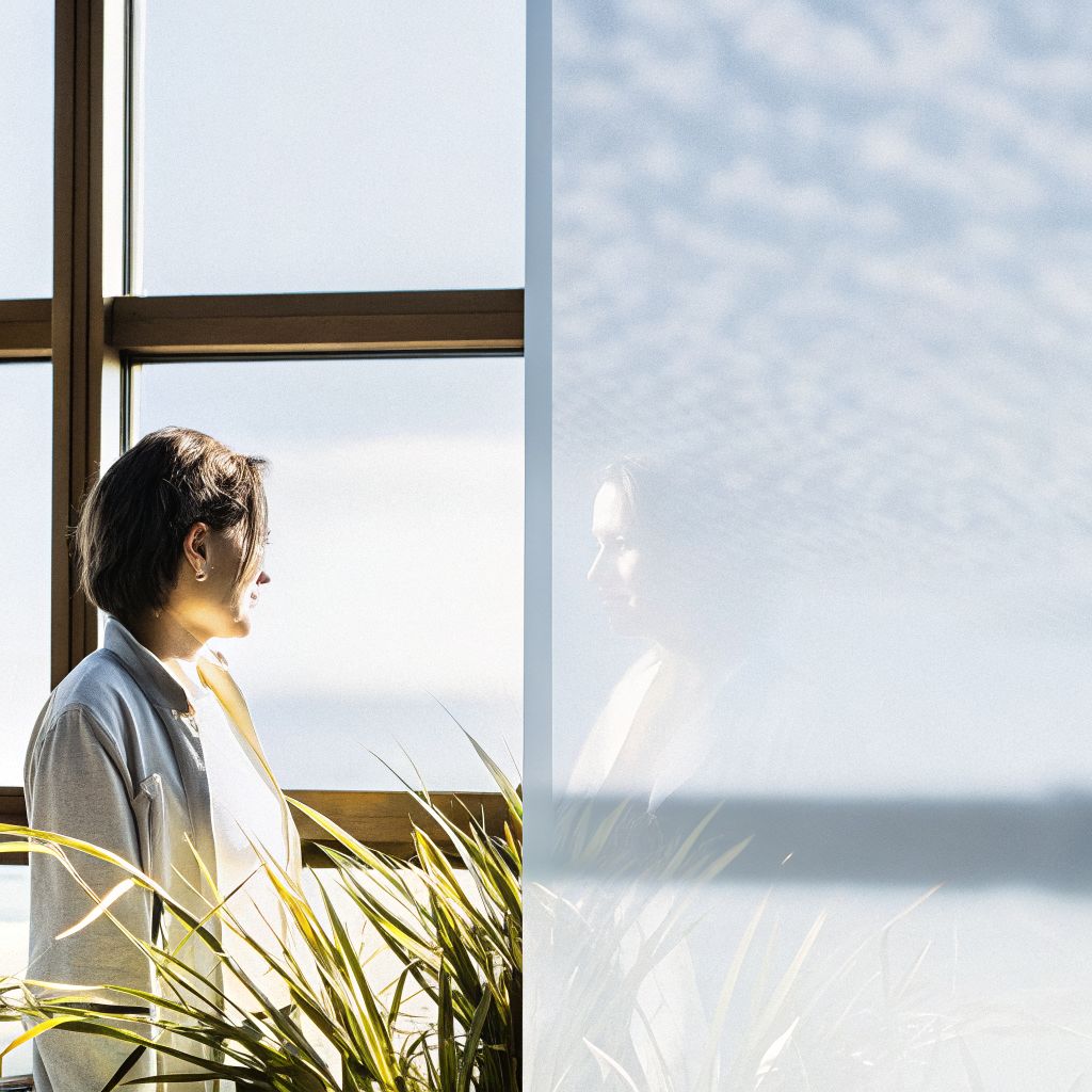 Person looking through a window with a subtle reflection