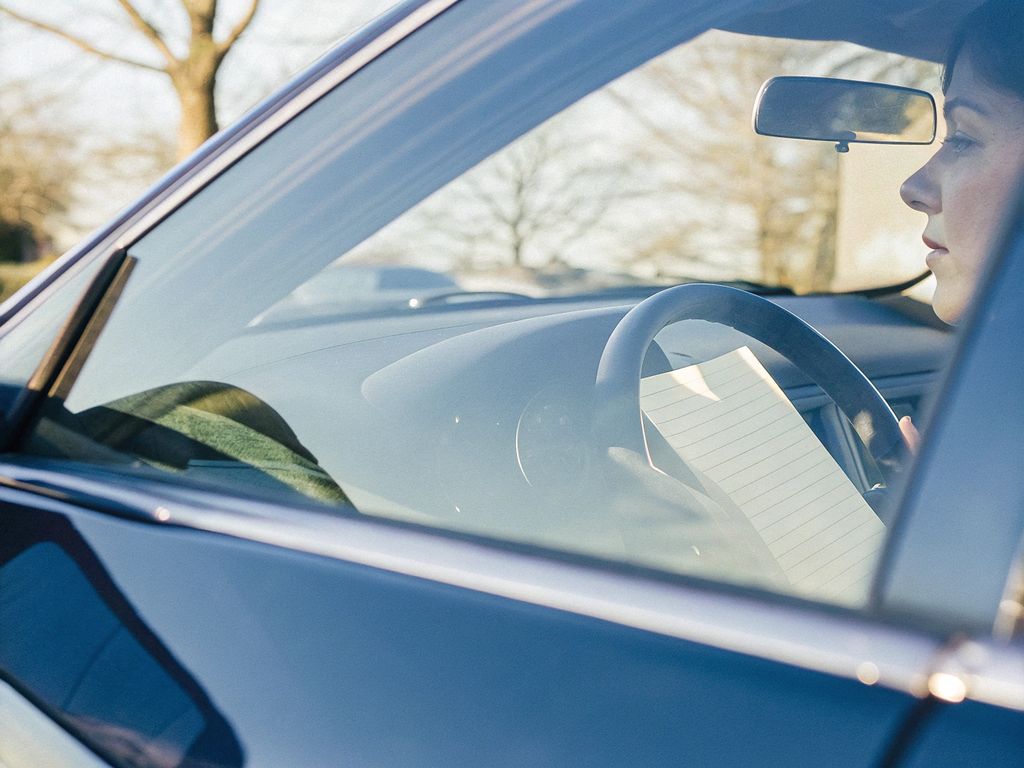 person quietly reflecting in their car after work