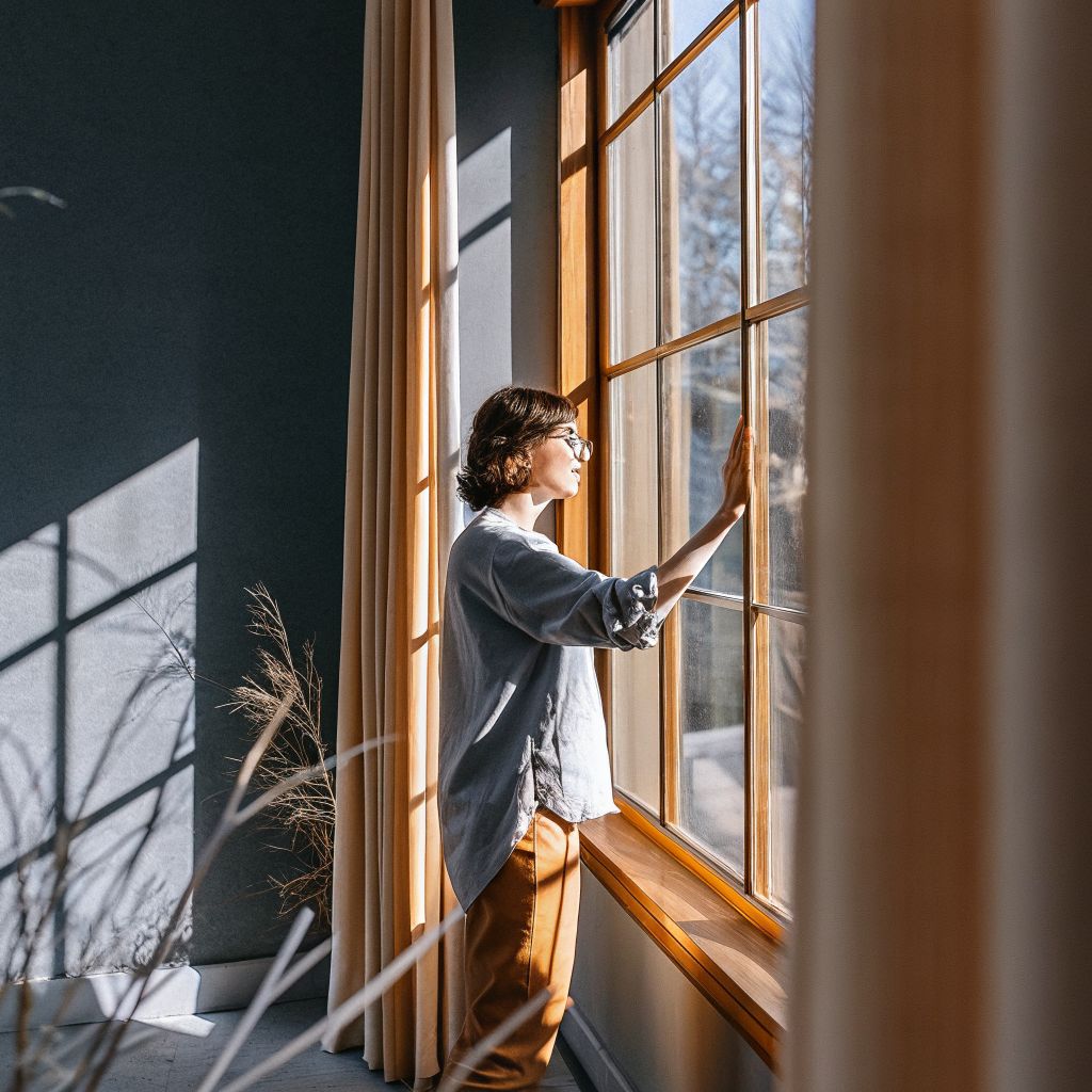 Person pausing by a window, soft daylight on their face