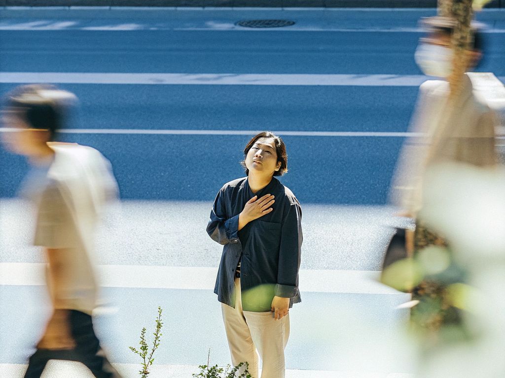 person pausing in a busy street, hand to chest