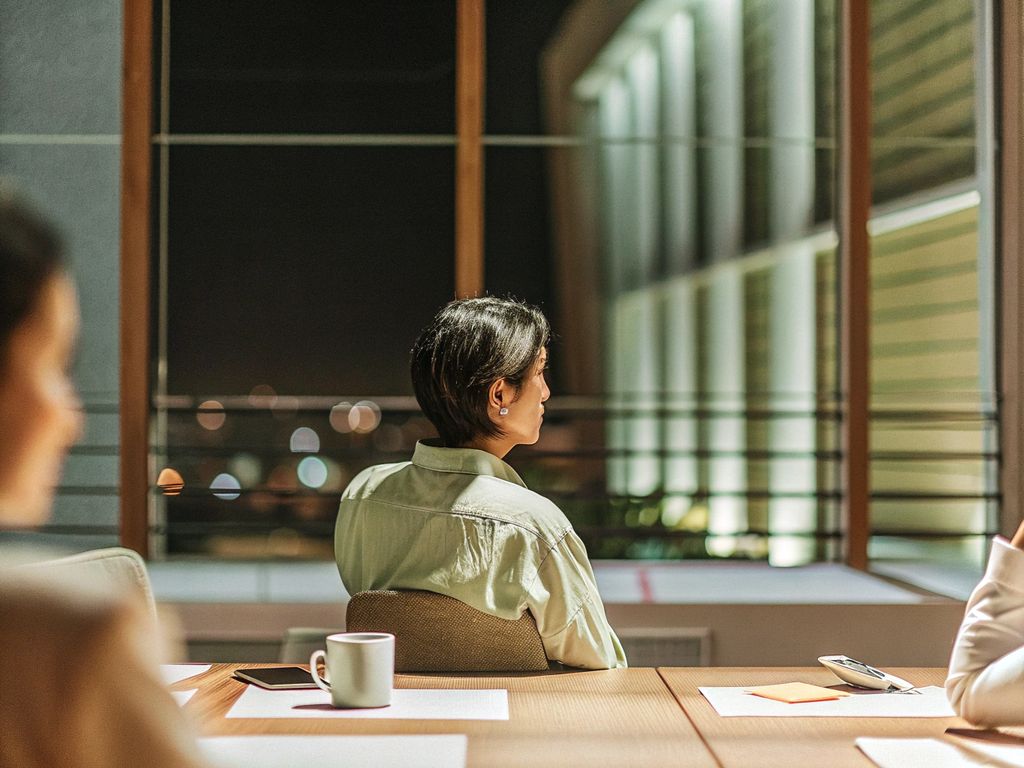 leader alone in dim office at night, city lights outside window