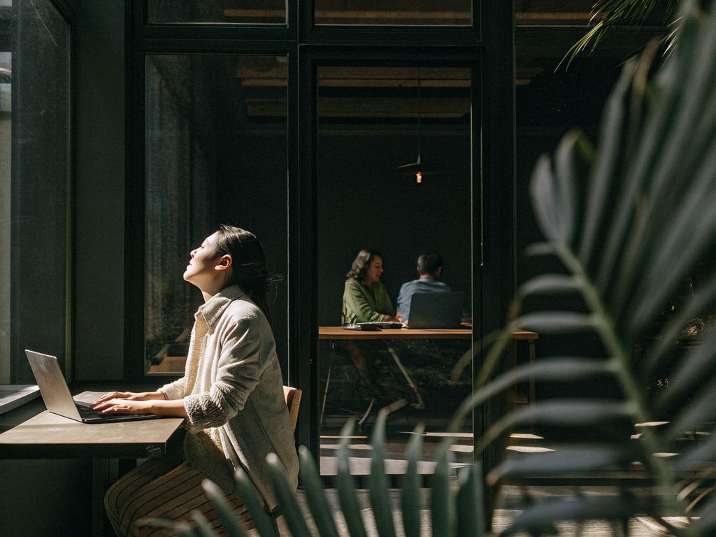 Focused young entrepreneur with closed eyes amid busy office