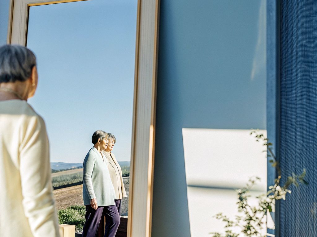 Person looking into a mirror with repeating landscape patterns