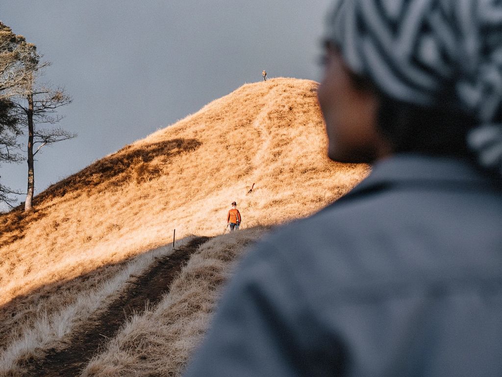 person standing at the base of a steep hill, pausing before climbing