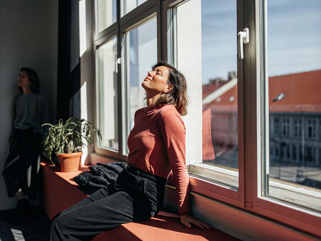 woman reflecting calmly near a city window