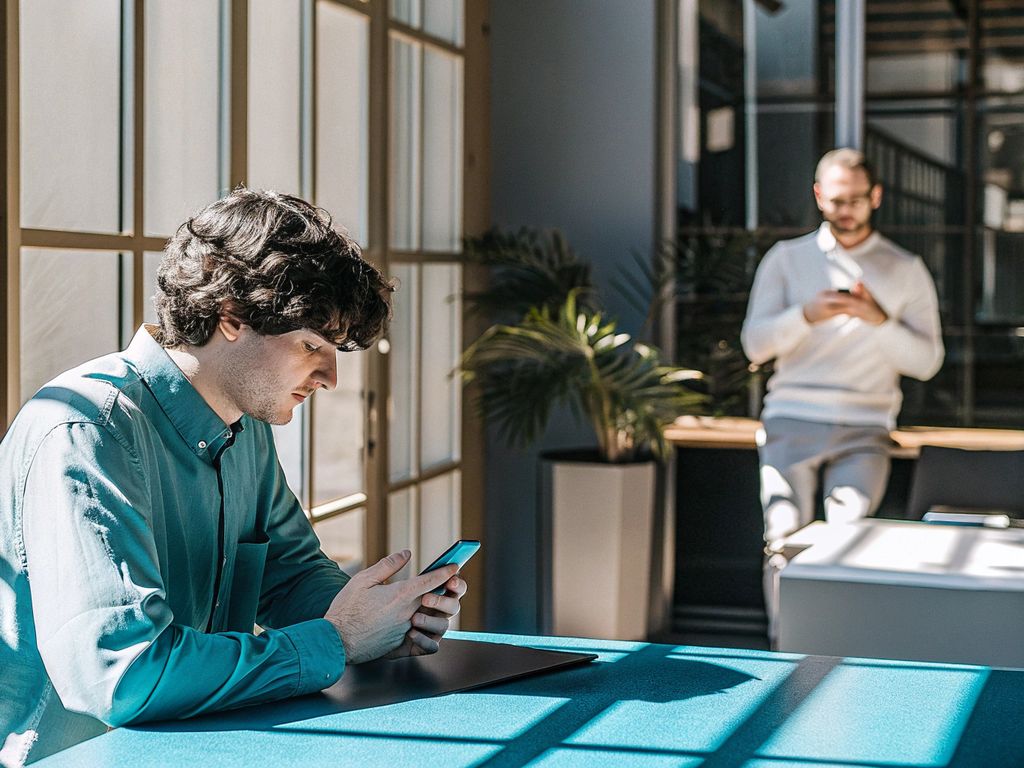 young leader with smartphone, overwhelmed in busy office