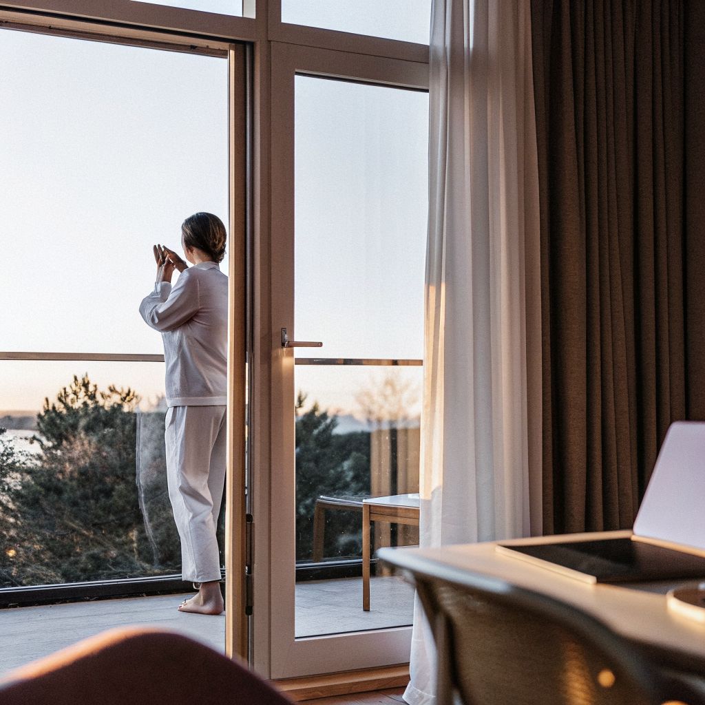 person pausing at a window overlooking a city