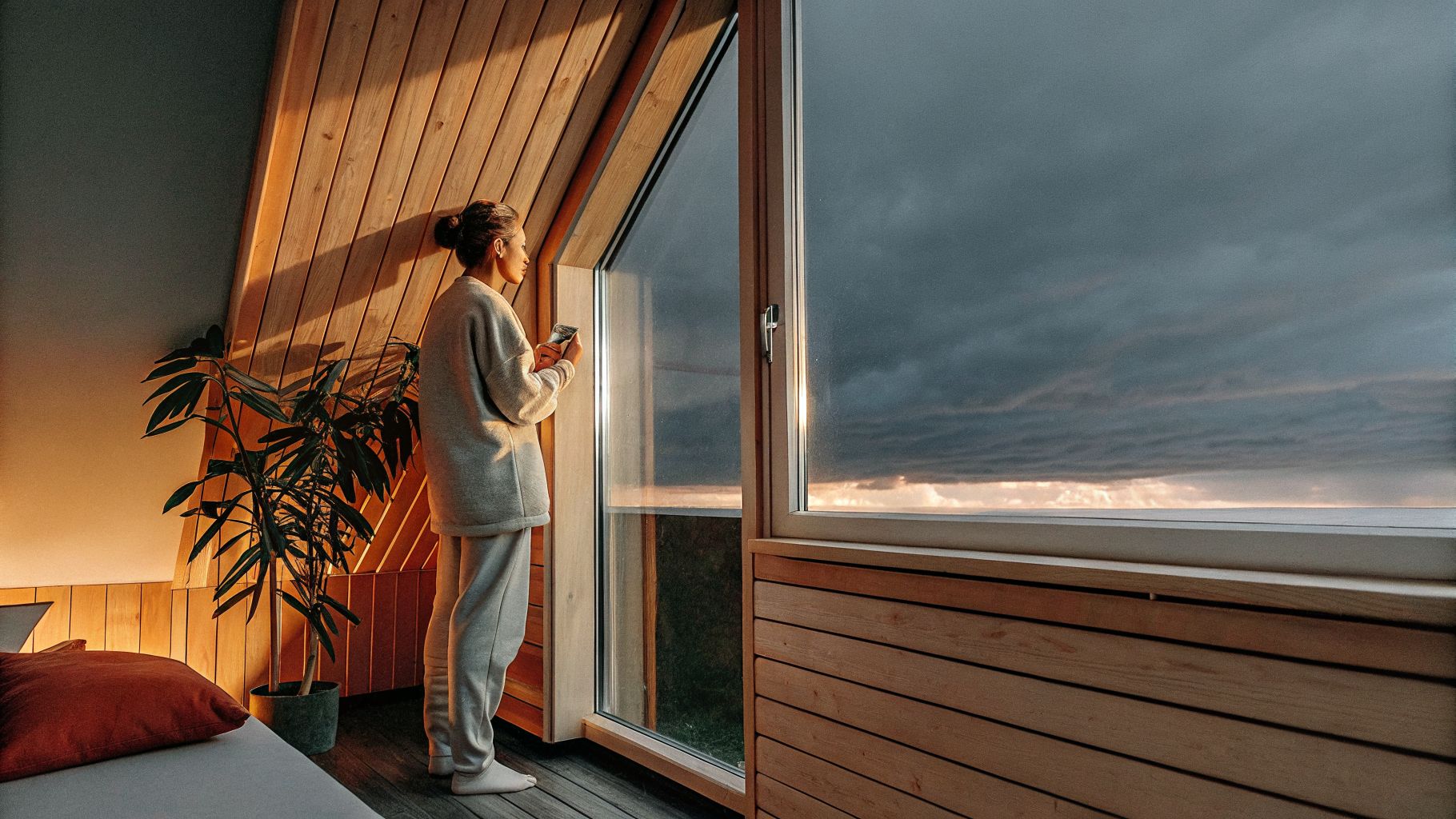 Inner transformation visual: person looking out a window as stormy sky shifts toward a calmer horizon