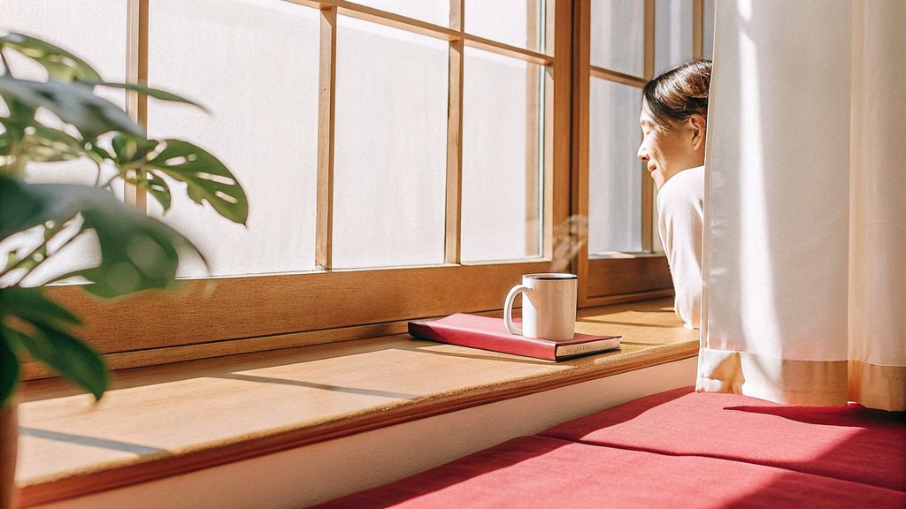 Person pausing by a window in soft morning light