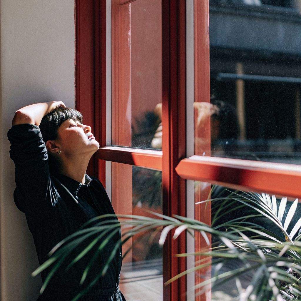 Person pausing by a city window, exhaling