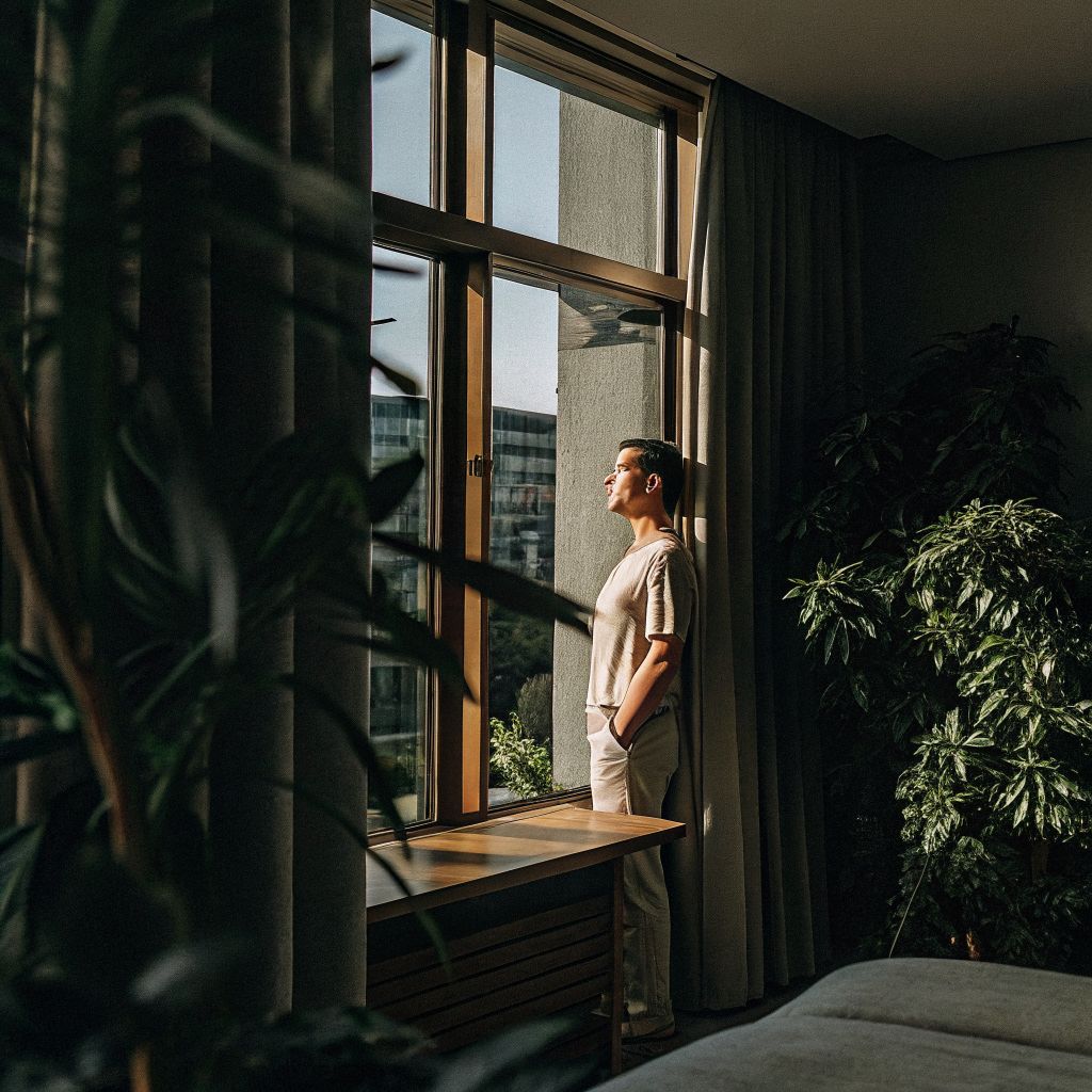 person pausing by a window with a city outside